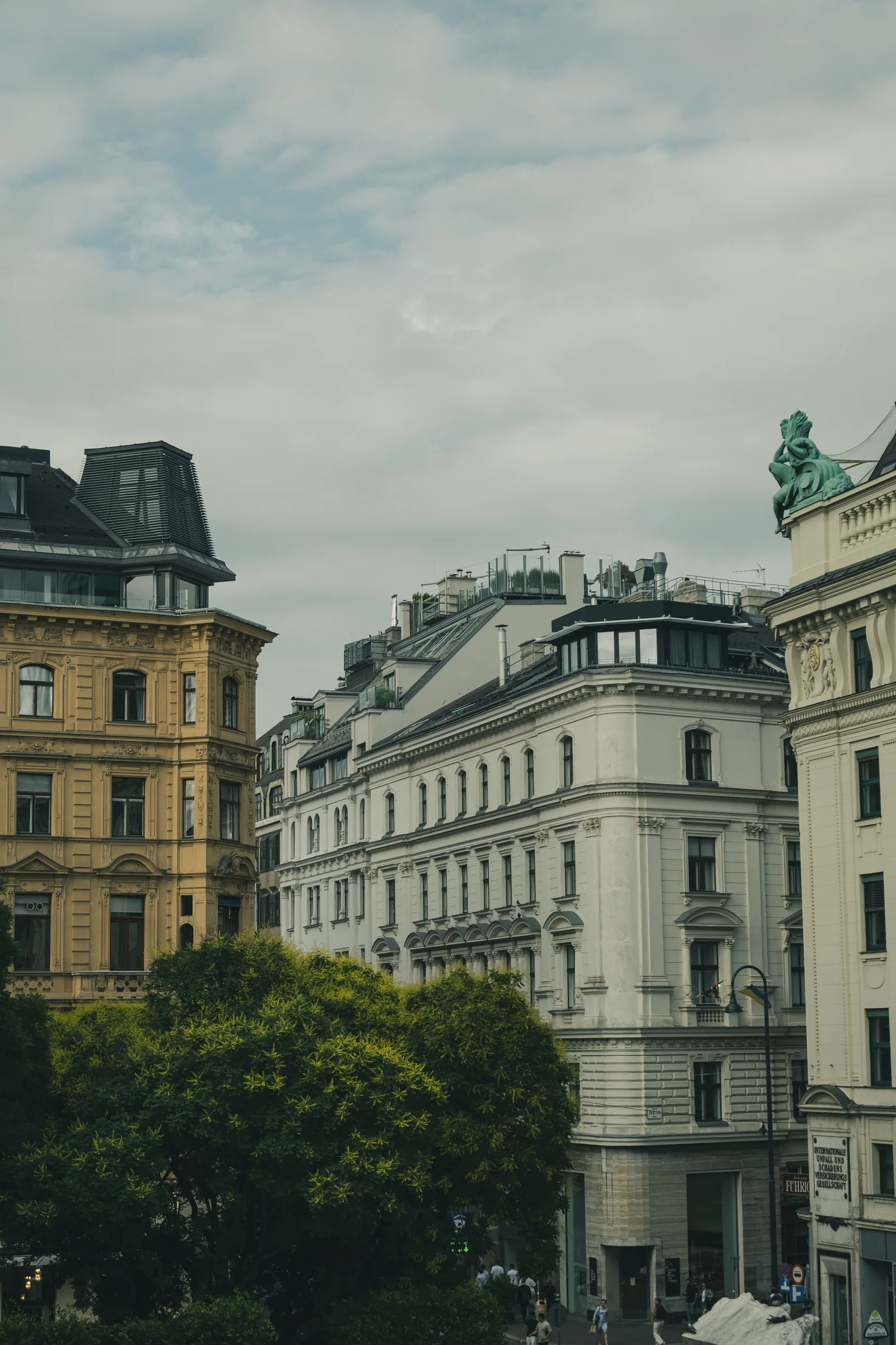 Historische Wiener Wohngebäude mit Bäumen und Geschäften im Erdgeschoss
